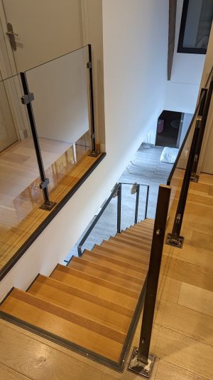 Escalier en métal avec des marches en bois et un garde-corps en métal avec panneau de verre