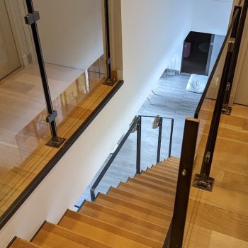 Escalier en métal avec des marches en bois et un garde-corps en métal avec panneau de verre